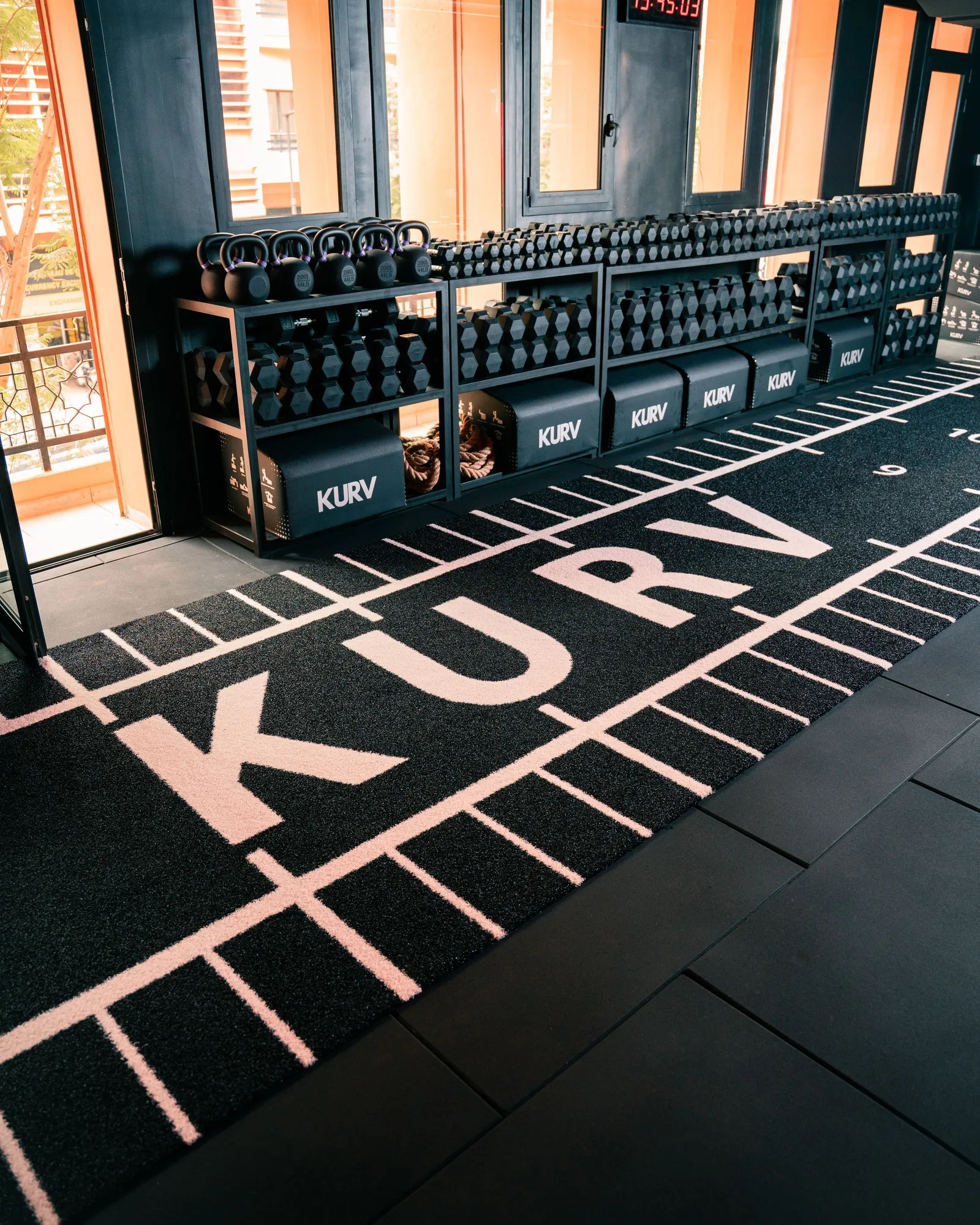 Le sol KURV floqué en crème sur le tapis noir, face aux racks d’haltères de Guéliz