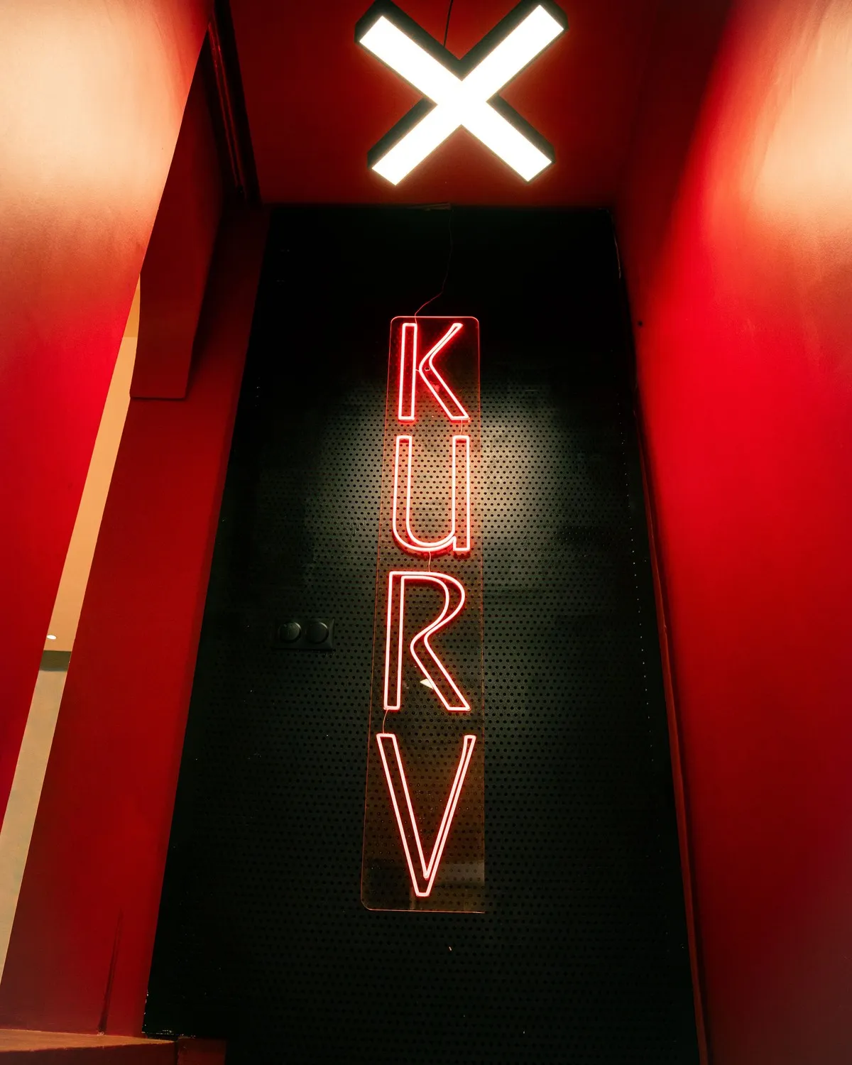 Le néon KURV dans la cage d’escalier rouge